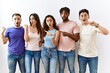 © Krakenimages.com - Group of young people standing together over isolated background surprised pointing with hand finger to the side, open mouth amazed expression.