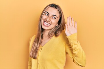 Poster - Beautiful hispanic woman wearing casual yellow sweater waiving saying hello happy and smiling, friendly welcome gesture