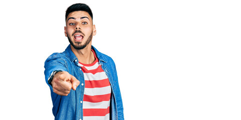 Wall Mural - Young hispanic man with beard wearing casual denim jacket pointing displeased and frustrated to the camera, angry and furious with you