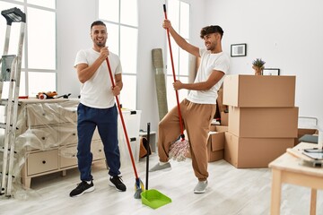 Sticker - Two hispanic men couple cleaning and dancing at new home