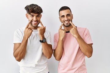 Sticker - Young gay couple standing over isolated background smiling with open mouth, fingers pointing and forcing cheerful smile