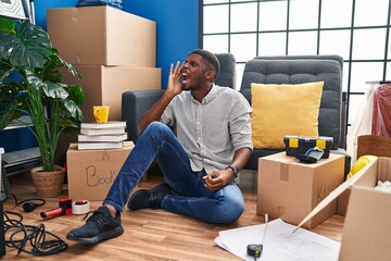 Poster - African american man sitting on the floor at new home shouting and screaming loud to side with hand on mouth. communication concept.