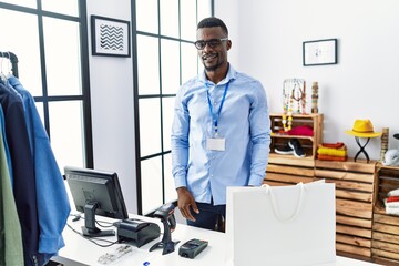 Wall Mural - Young african man working as manager at retail boutique winking looking at the camera with sexy expression, cheerful and happy face.