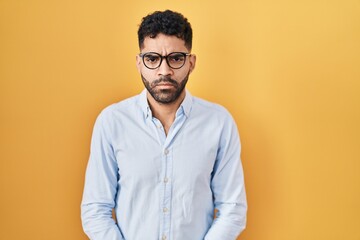 Wall Mural - Hispanic man with beard standing over yellow background skeptic and nervous, frowning upset because of problem. negative person.