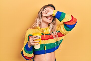 Sticker - Beautiful young blonde woman drinking cup of coffee wearing headphones smiling cheerful playing peek a boo with hands showing face. surprised and exited