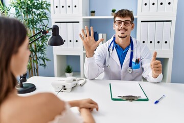 Canvas Print - Young doctor with client at medical clinic showing and pointing up with fingers number six while smiling confident and happy.