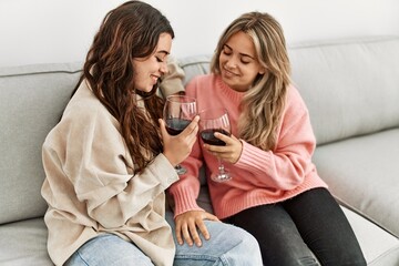 Poster - Young couple smiling happy toasting with red wine glass at home.