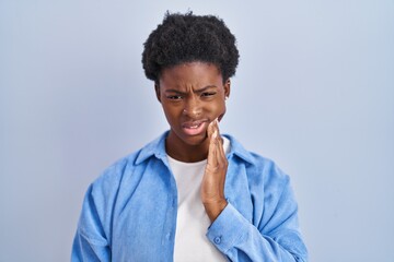 Canvas Print - African american woman standing over blue background touching mouth with hand with painful expression because of toothache or dental illness on teeth. dentist