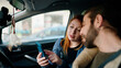 © Krakenimages.com - Man and woman couple using smartphone driving car at street