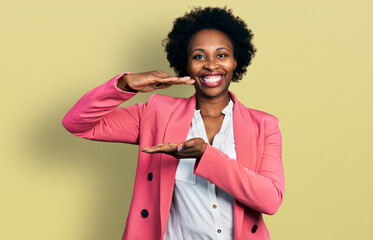 Canvas Print - African american woman with afro hair wearing business jacket gesturing with hands showing big and large size sign, measure symbol. smiling looking at the camera. measuring concept.