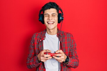 Canvas Print - Young hispanic man playing video game holding controller celebrating crazy and amazed for success with open eyes screaming excited.