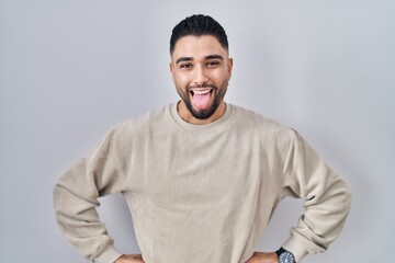 Sticker - Young handsome man standing over isolated background sticking tongue out happy with funny expression. emotion concept.