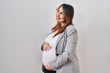 Poster - Pregnant business woman standing over white background looking away to side with smile on face, natural expression. laughing confident.