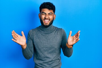 Sticker - Arab man with beard wearing turtleneck sweater celebrating mad and crazy for success with arms raised and closed eyes screaming excited. winner concept