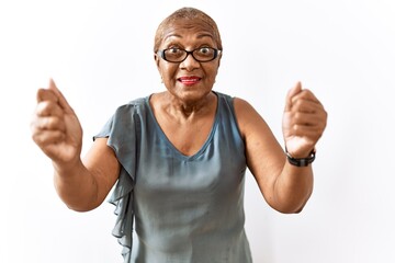 Poster - Mature hispanic woman wearing glasses standing over isolated background shouting frustrated with rage, hands trying to strangle, yelling mad