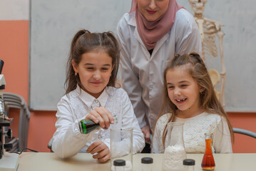 Wall Mural - Kids scientists with a female Muslim teacher doing chemistry science experiments in the school lab.