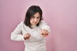 © Krakenimages.com - Woman with down syndrome standing over pink background punching fist to fight, aggressive and angry attack, threat and violence
