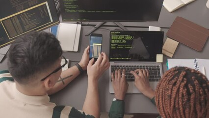 Top view slowmo of two young diverse programmers working with programming code at workplace