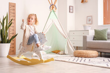 Cute Little Girl Playing With Rocking Horse At Home