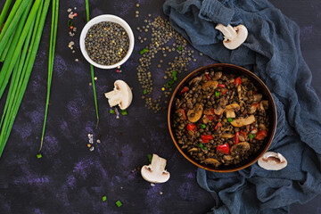 Delicious lentils with pepper and mushrooms on dark background