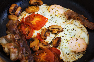 Fried eggs with bacon, tomatoes and mushrooms on white background. Top view