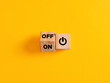 The words on and off on wooden cubes with start icon on yellow background. Power on off switch or start and stop button