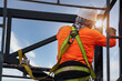 © tong2530 - Industrial steel roof truss welder with Fall arrestor device for worker with hooks for safety body harness on the construction site.