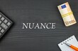 NUANCE - word (text) and euro money on a wooden background, calculator, pen and notepad. Business concept (copy space).