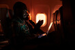 © DC Studio - Male passenger browsing internet on laptop and flying abroad in airplane, using international airline to travel on business work trip. Young man working on computer and travelling during sunset.