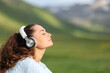 © Antonioguillem - Woman with headphones relaxing listening audio in the mountain