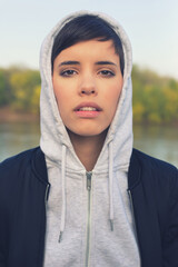 Wall Mural - Portrait of young woman outdoors wearing hoodie 