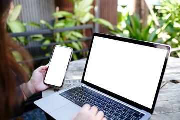 mockup image computer,cell phone blank screen for hand typing text,using laptop contact business searching information in workplace on desk at office.design creative work space on wooden desk