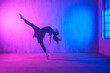 Leinwandbild Motiv Modern dance girl dancer dancing in neon light doing gymnastic exercises in studio, copy space.