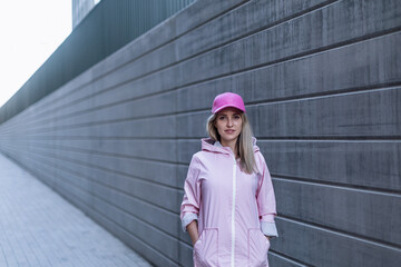 Poster - Young woman in fashion clothes standing in city concrete wall.