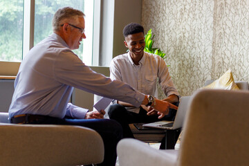 Wall Mural - Businessman explaining strategies over laptop to coworker