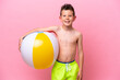 © luismolinero - Little caucasian boy holding a beach ball isolated on pink background smiling a lot