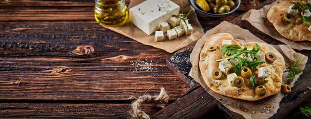 Delicious homemade flatbread with cheese olives and herbs on table