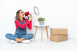 © luismolinero - Young caucasian woman sitting on the floor among boxes shouting through a megaphone