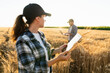 © scharfsinn86 - Couple of farmers examines the field of cereals and sends data to the cloud from the digital tablet and laptop. Smart farming and digital agriculture.