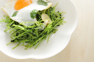 Wall Mural - Chinese food, Pea sprouts stir fried vegetable with sunny side up fried egg on top