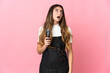 © luismolinero - Young hairdresser woman isolated on pink background looking up and with surprised expression