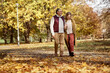 © gpointstudio - Senior woman and man walking together at the park during the autumn