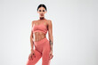 © halayalex - Tanned fitness woman in pink sports clothing. Sexy young beautiful model with perfect body.Female isolated on grey background in studio. Stretching out before training