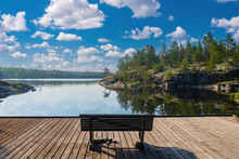 Lake Ladoga In Karelia. Rest In Russia. Empty Bench On Pier. Place To Enjoy Nature. Picturesque Landscape With Lake Ladoga. Wooden Pier In Karelia. Blue Sky Karelia. Rocks With Pine Forest In Russia