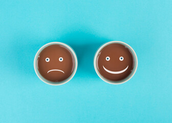 Wall Mural - Cup of coffee with a sad and a happy face, positive and negative mindset, support and evaluation concept, emotion