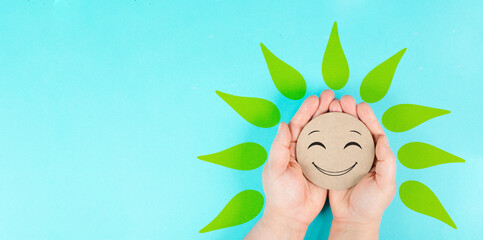 Wall Mural - Holding a smiling face with green petals in the hands, mental health concept, positive mindset, support and evaluation symbol
