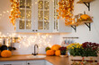 © sergiophoto - Autumn kitchen interior. Red and yellow leaves and flowers in the vase and pumpkin on light background