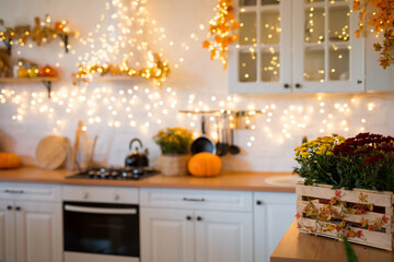 Autumn kitchen interior. Red and yellow leaves and flowers in the vase and pumpkin on light background