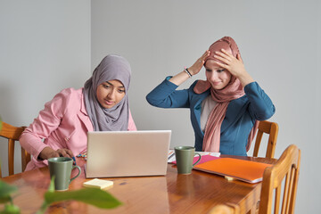 Two muslim female university students wearing hijab doing schoolwork after class. Morocco college students.