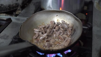 Sticker - Close up of pieces of meat cooking in a pan over high heat.